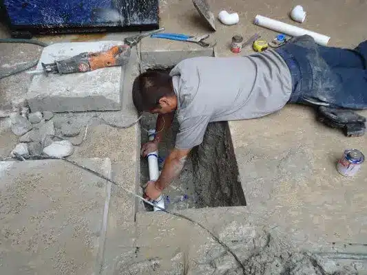 Technician repairing a burst pipe under a Midwest City, OK kitchen sink during an emergency service call