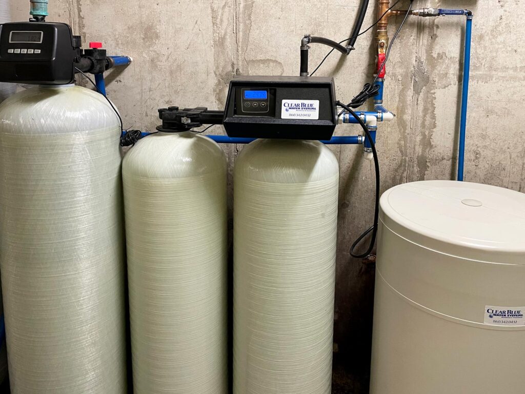 Technician installing whole-home water filtration system beside garage water line in Moore residence