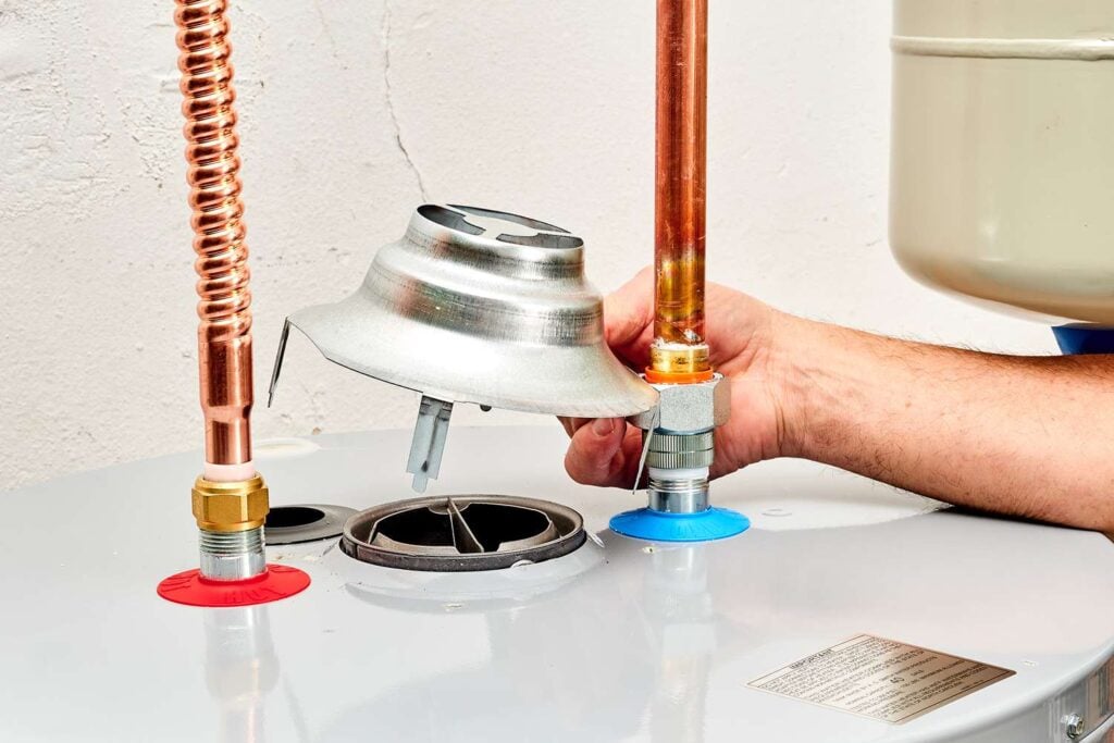 Technician replacing leaking water heater in Yukon garage utility closet