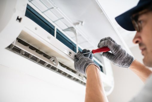 Technician replacing a failed AC capacitor in a Midwest City residential home during a summer heatwave emergency