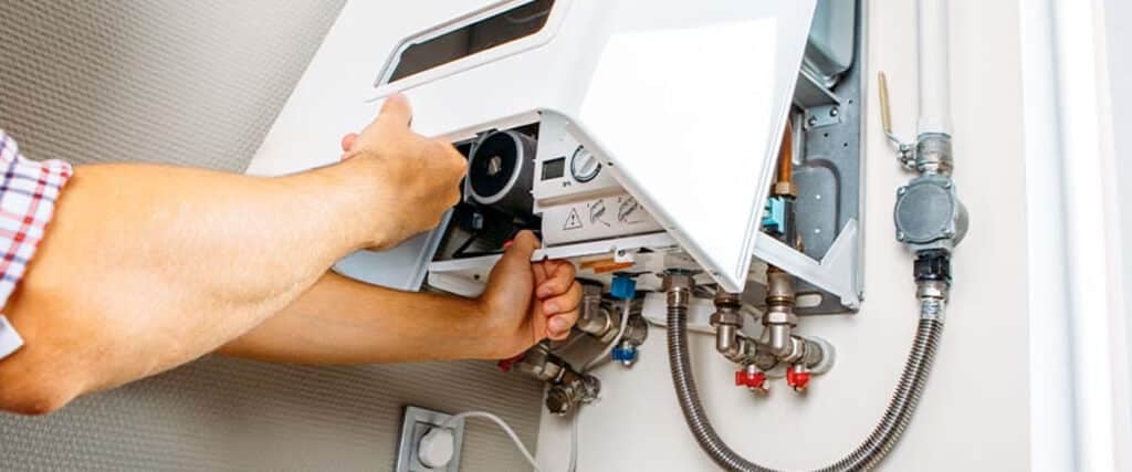 Experienced technician diagnosing water heater in commercial Edmond property with specialized equipment and safety gear