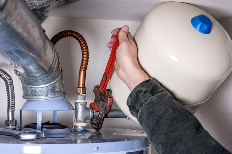 Technician replacing water heater thermostat in an Edmond, OK rental property utility room