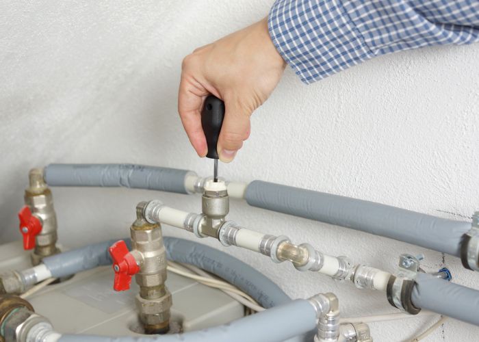 Technician examining water heater connections in a luxury Nichols Hills, OK home with advanced plumbing features